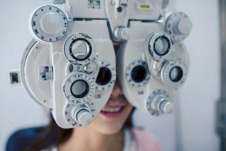 woman looking through phoropter